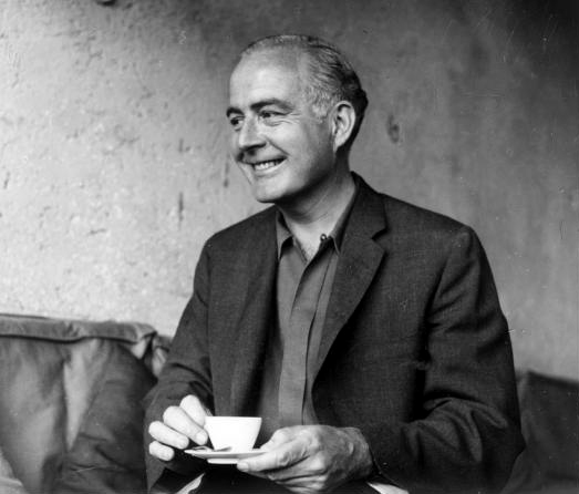 Le compositeur Samuel Barber assis sur un canapé tenant dans ses mains une tasse de thé